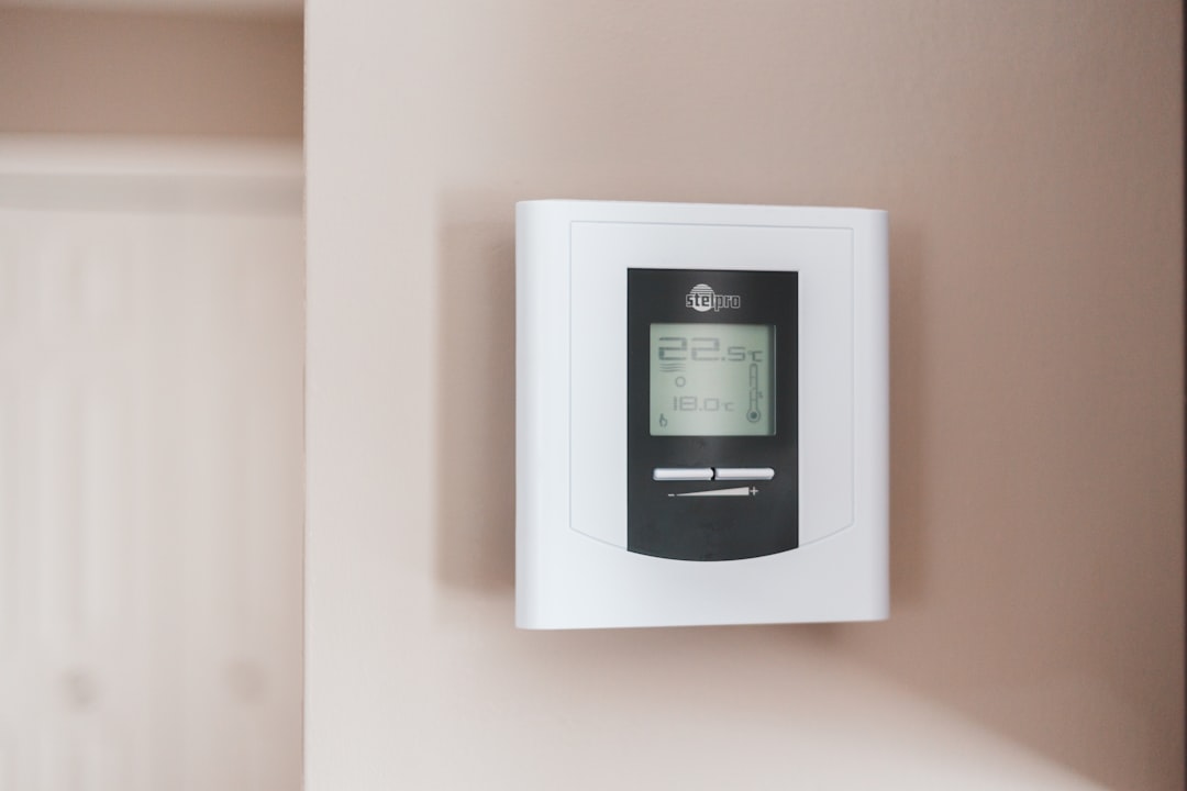 White programmable thermostat mounted on wall showing temperature display