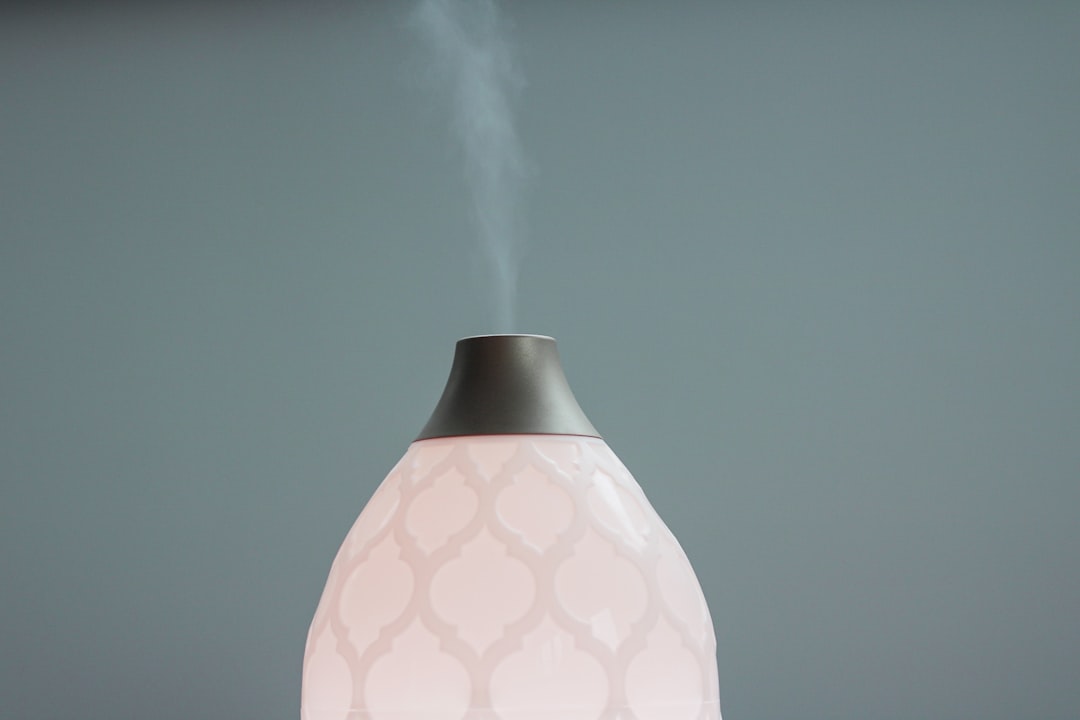 White ultrasonic humidifier emitting cool mist on a wooden surface